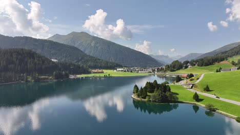 vuelo de avión no tripulado sobre el lago davos, capturando el reflejo de las montañas en el agua, y revelando la famosa ciudad de davos enclavada en los alpes suizos