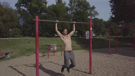 Beautiful-fit-young-man-doing-pull-ups-in-the-park,-male-athlete-doing-exercise-and-spending-active-time