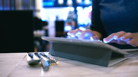 Woman-typing-message-or-e-mail-on-pad-in-cafe