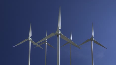 row of wind power generators on blue sky background. seamless looping animation of wind turbines spinning