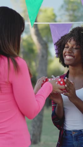 friends exchanging a gift at an outdoor celebration