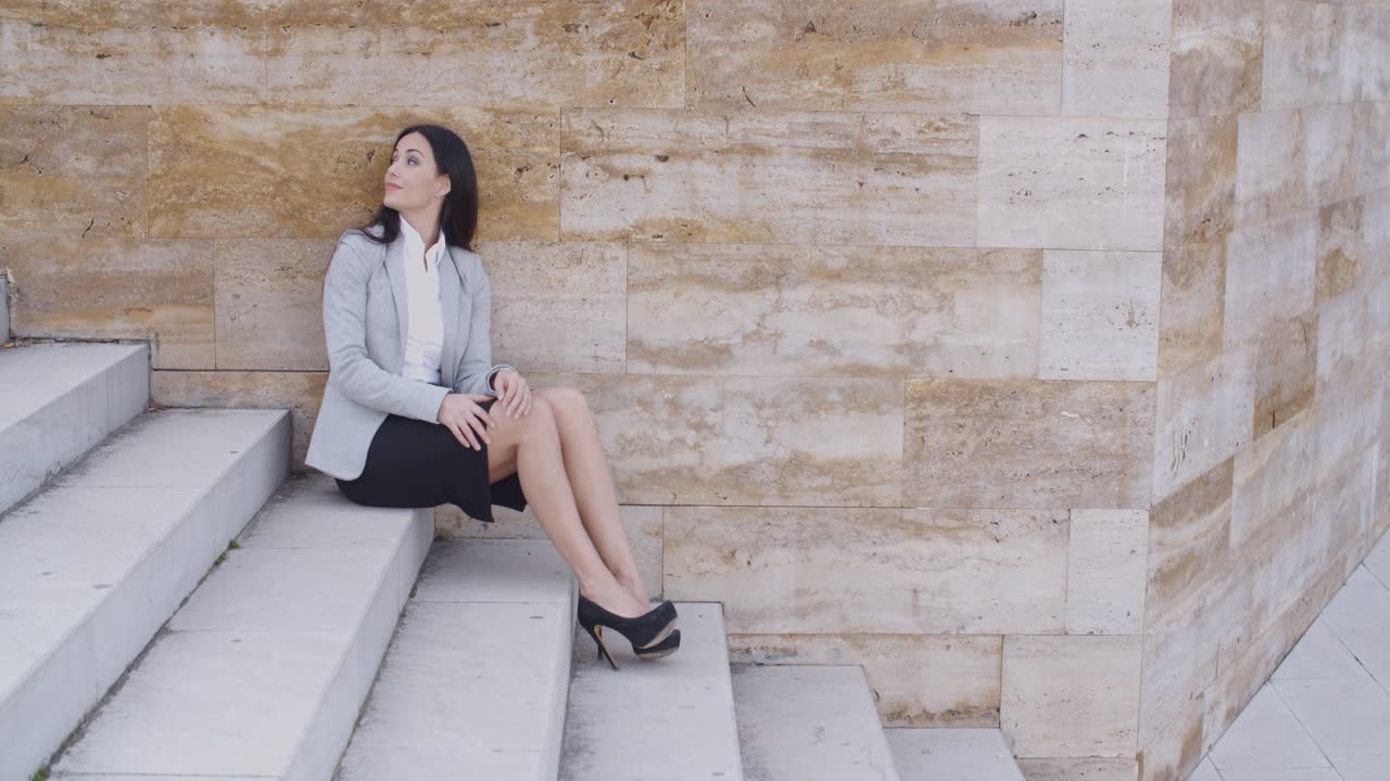 Serious woman sitting on stairs outdoors