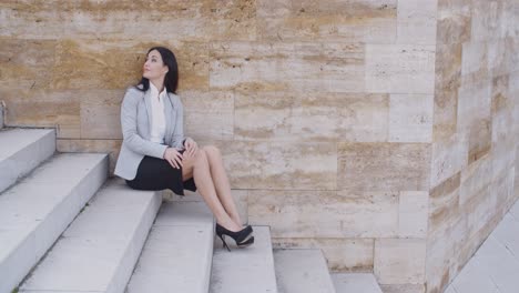 Serious-woman-sitting-on-stairs-outdoors