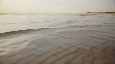 Camera gliding over calm shallow waters, showing sand textures on the seafloor