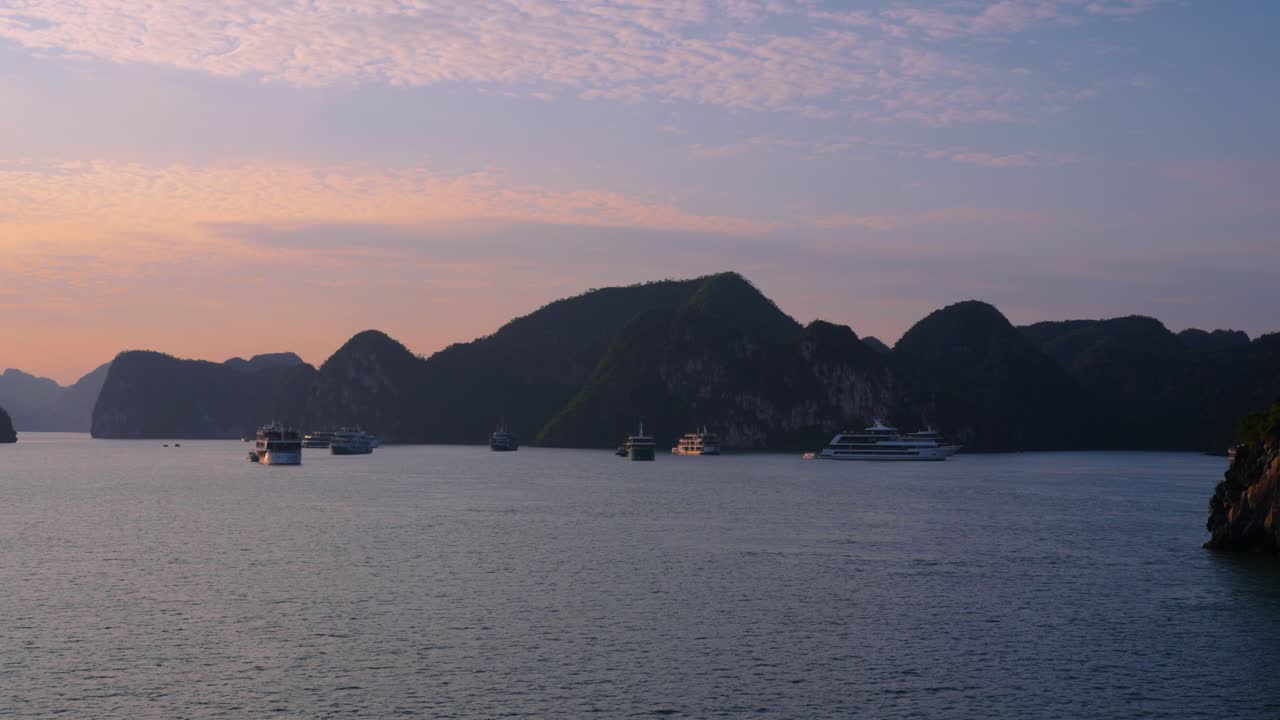 Sunset Golden Hour Cruise through Ha Long Bay Vietnam. Sailing through a UNESCO World Heritage site as the sun sets across the limestone cliffs and mountains.