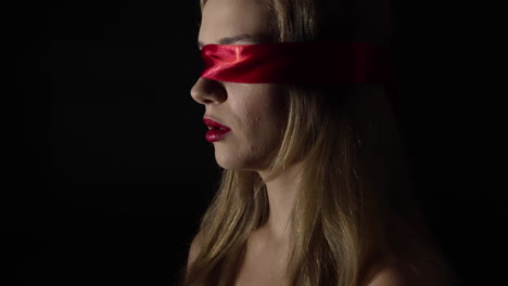 portrait of the young woman blindfold with red ribbon