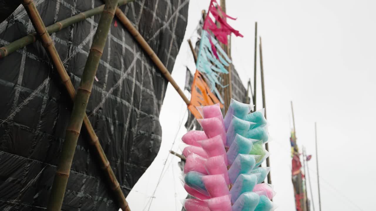 Pink and blue cotton candy displayed beside giant kites at Sumpango festival