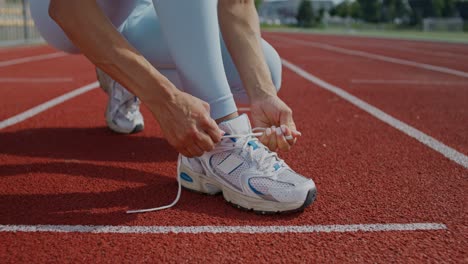 woman tying running shoes on track