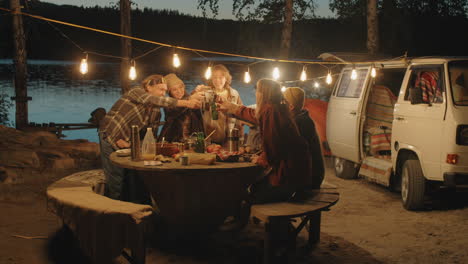Jóvenes-Amigos-Tintineando-Bebidas-En-Brindis-En-La-Cena-De-Camping