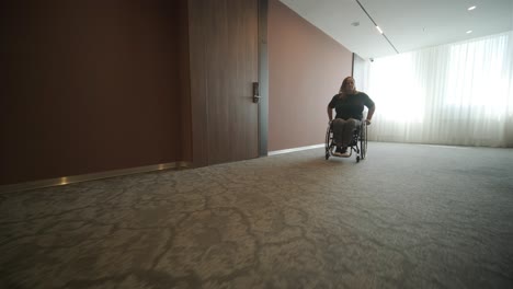 a woman in a wheelchair moves down a spacious hotel hallway, highlighting accessibility and independence in modern travel accommodations. the image emphasizes inclusive design and ease of mobility.