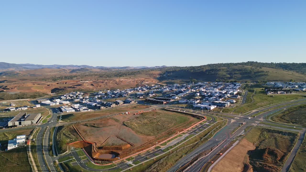 Aerial footage showing a Canberra housing development from afar, nestled beside open fields and rolling terrain.