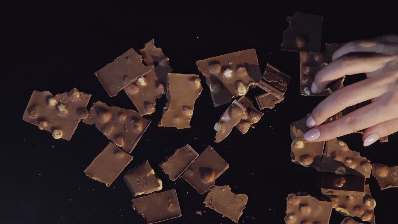 여성의 손은 초콜릿 조각의 어리에서 초콜릿의 조각을 가져갑니다