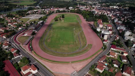 Toma-Aérea-Retrocediendo-Que-Revela-El-Hipódromo-De-La-Ciudad-De-Feurs-Y-La-Ciudad-Al-Fondo,-Provincia-De-Forez,-Departamento-De-Loira,-Región-De-Auvernia-Ródano-Alpes,-Francia