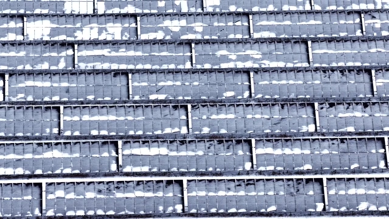 Solcellepaneler i nærbilde som viser individuelle celler delvis tildekket av snø på et jorde