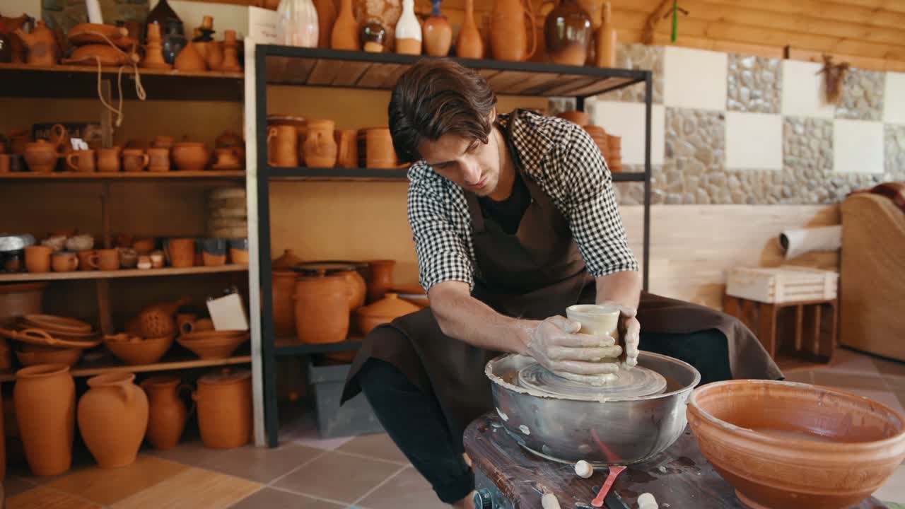 el ceramista utiliza la rueda del alfarero y crea un producto de arcilla hecho a mano
