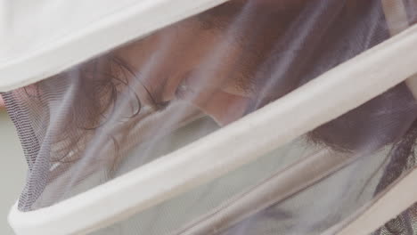 apiarist in protective white suit focused on task at hand at beehive, profile