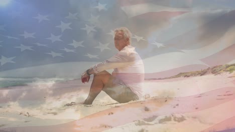 animation of senior caucasian man sitting on beach over flag of united states of america