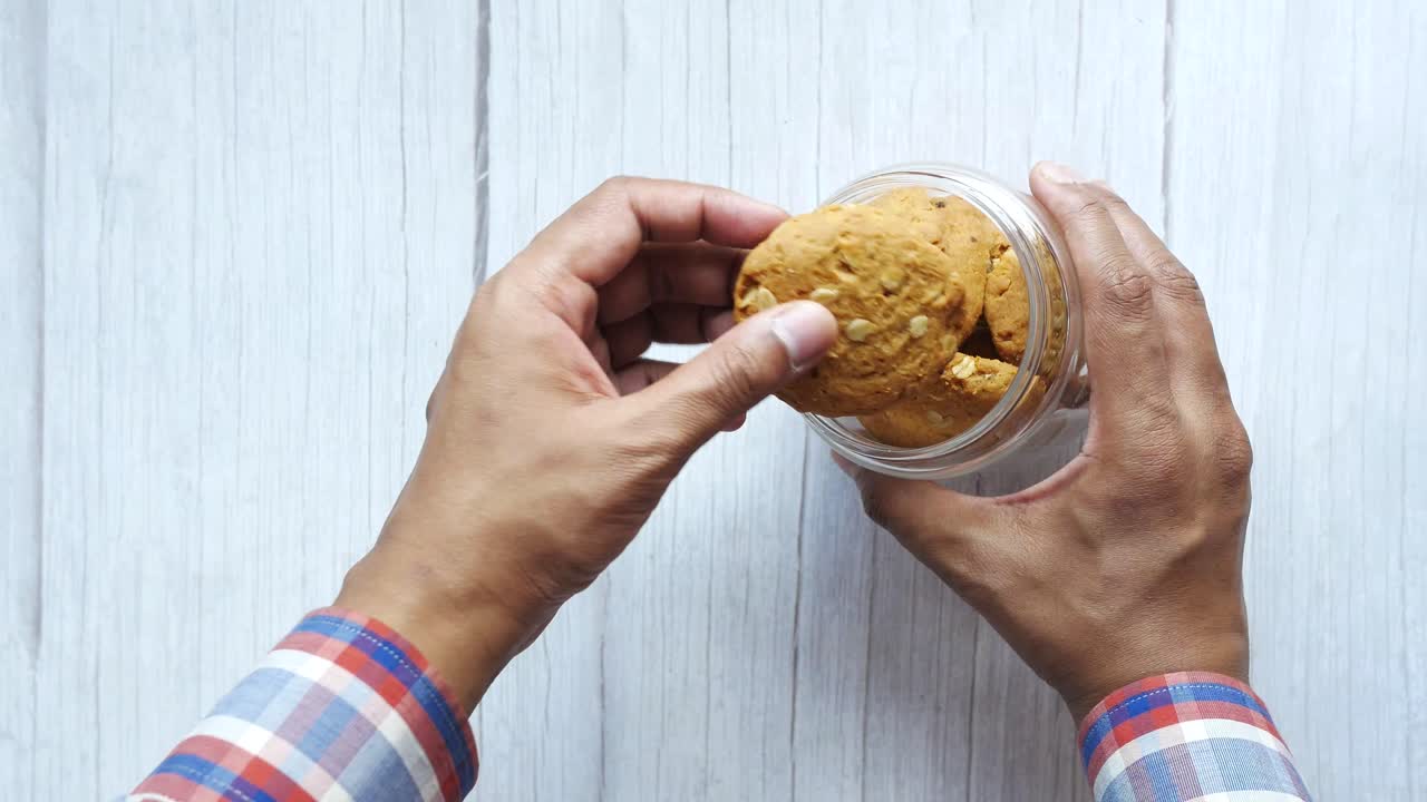 persona sosteniendo un frasco de vidrio de galletas de avena