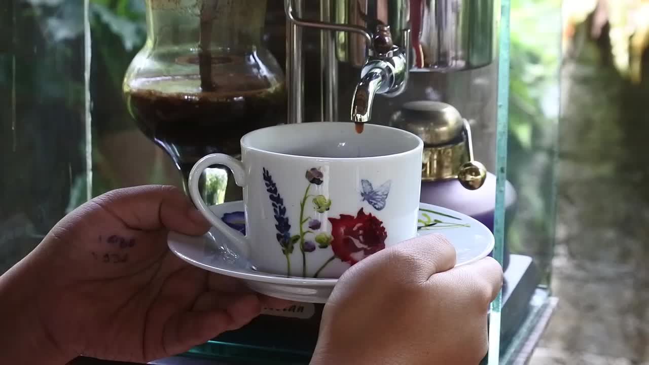 disparo de cerca de la mano sosteniendo una taza de café mientras espera que gotee