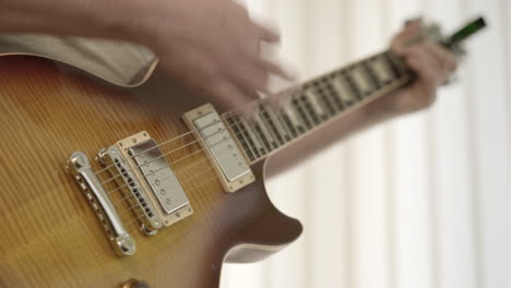 shallow dof close-up of a male musician's hands playing a sunburst electric guitar