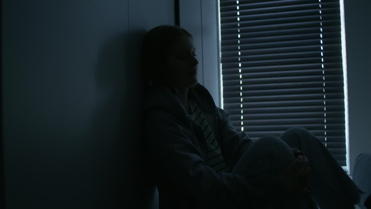 Donna seduta da sola in una stanza buia