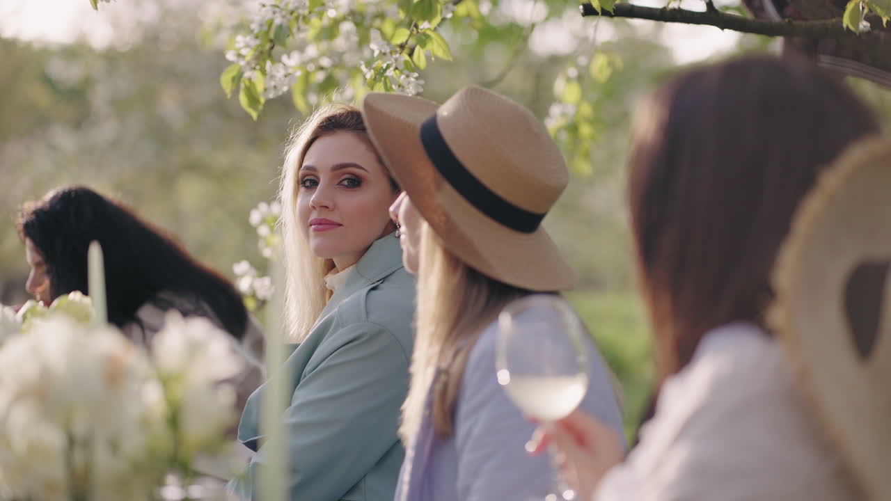 아름다운 여성들은 꽃 피는 정원에서 점심을 먹고 봄날과 맛있는 식사를 즐기고 있습니다.