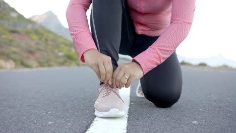 preparing for mountain hike, woman tying shoelaces on road