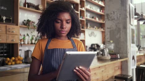 thoughtful female cafe owner using digital tablet