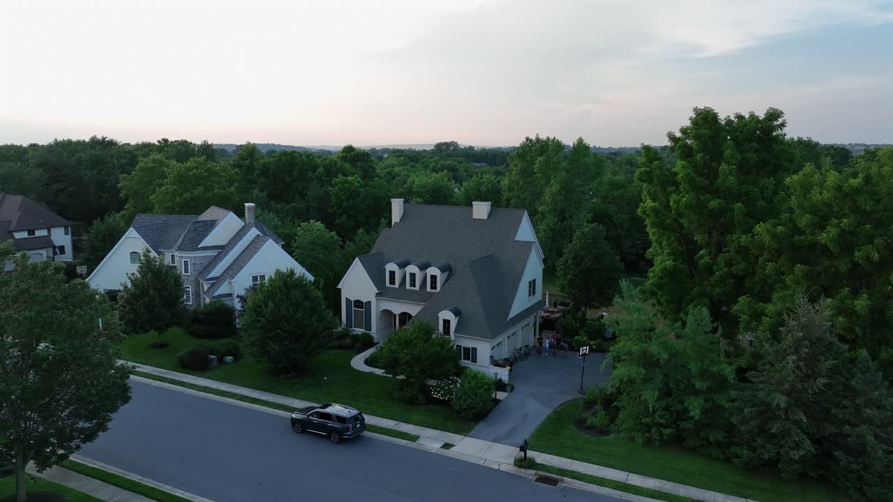 Aerial view of American township with colonial-style suburban homes, pitched roofs, dormer windows and tree-lined streets in peaceful residential neighborhood. Dusk scene in Pennsylvania