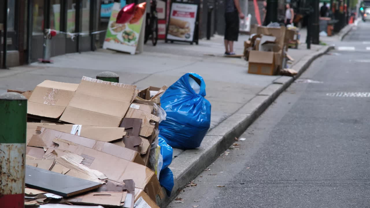 Discarded cardboard boxes and blue trash bags clutter the sidewalk in Center City Philadelphia