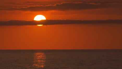 big orange sun with clouds over ocean at sunrise, mediterranean dawn