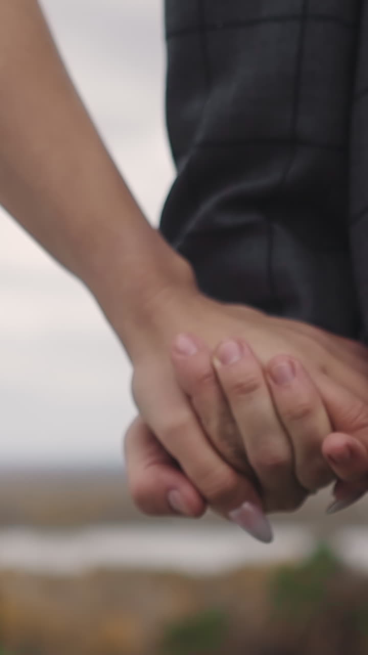 Young newlywed family joins hands walking together along spring park closeup slow motion. Couple loving relationship. Marriage celebration day