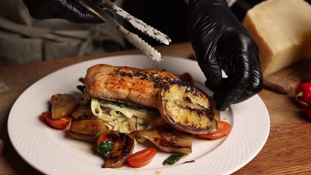 Chef Plating Gourmet Salmon Pasta Dish with Grilled Lemon