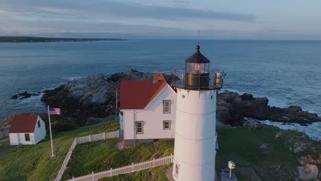 aerial drone shot of york beach maine flying around cape neddick nubble lighthouse at sunset