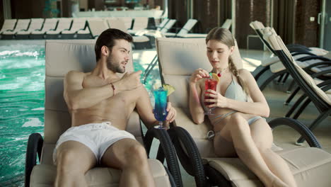 Closeup-couple-drinking-cocktails-in-deckchair.-Man-and-woman-flirting-together