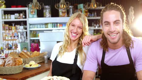 Portrait-of-smiling-waiter-and-waitress-standing-at-counter