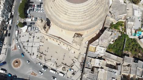 Bird's-eye-view-aerial-4k-drone-footage-flying-over-the-Mosta-Rotunda-Dome,-a-Roman-Catholic-church,-and-it's-surrounding-city-of-Malta
