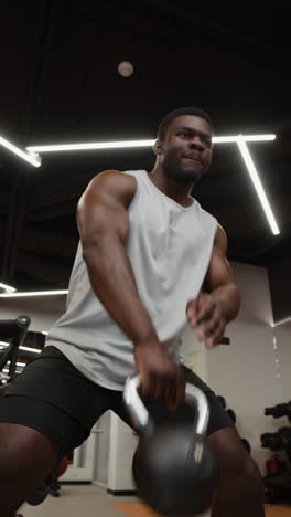 man performing kettlebell swings in gym