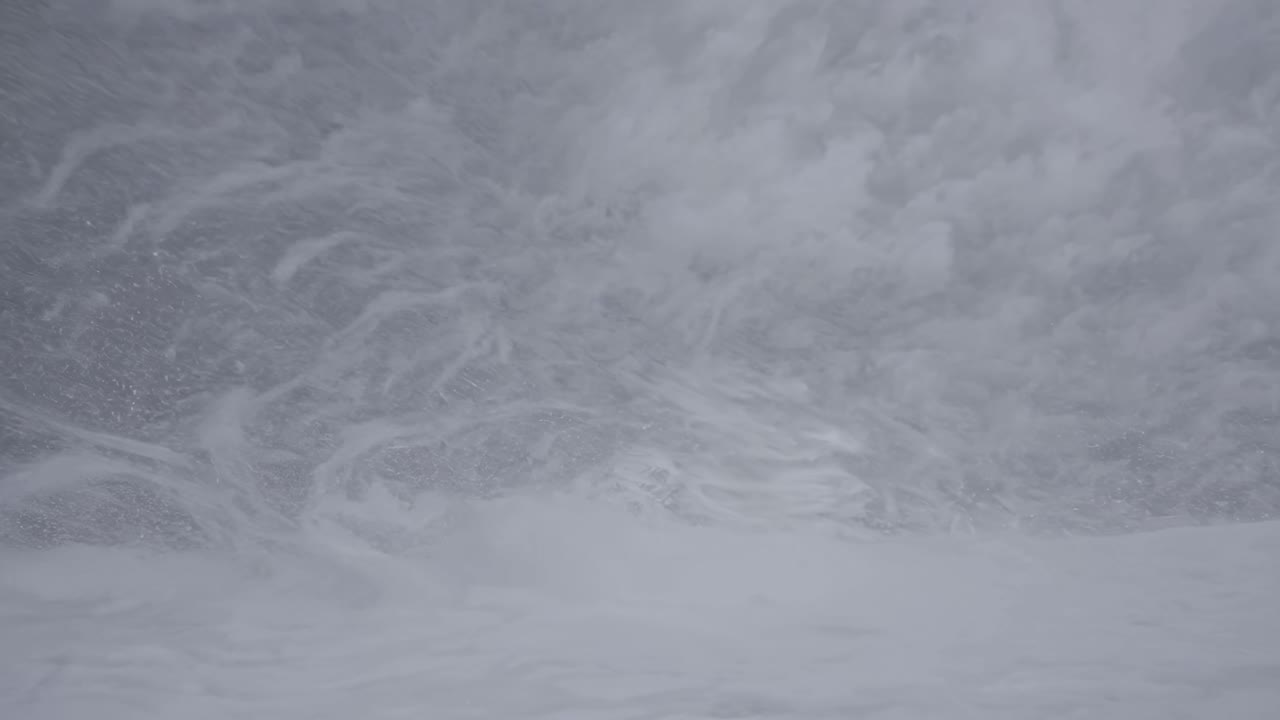 Aerial video shot of a snowstorm, capturing swirling snowflakes and overcast skies