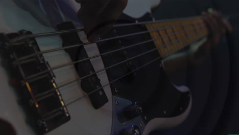 musician plucking bass guitar strings in dim music studio, displaying animated waveform graphics