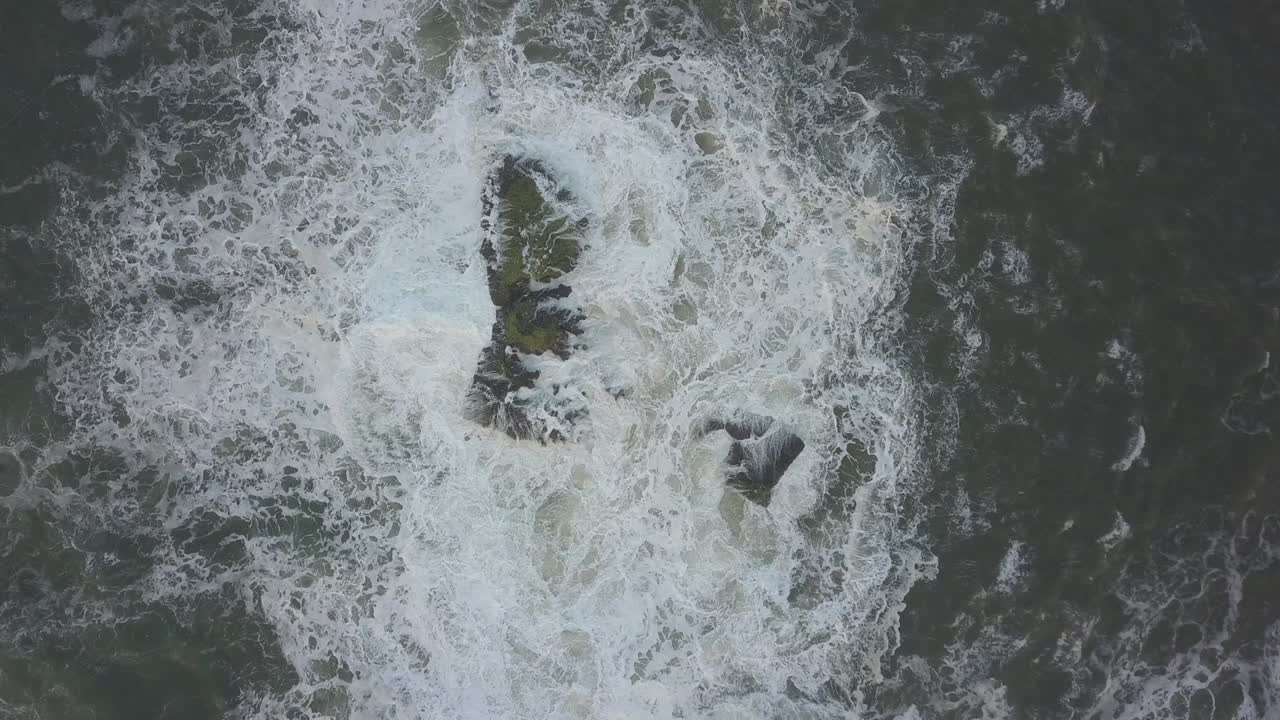 Waves crash against the rocks. An iconic place on the Atlantic coast, the Mecca of surfing on big waves.Rocks at the Nazare Lighthouse, the place with the largest waves in Europe, Nazare, Portugal.