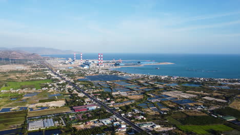 Aerial-view-on-coastal-highway-by-rice-fields-and-power-plant