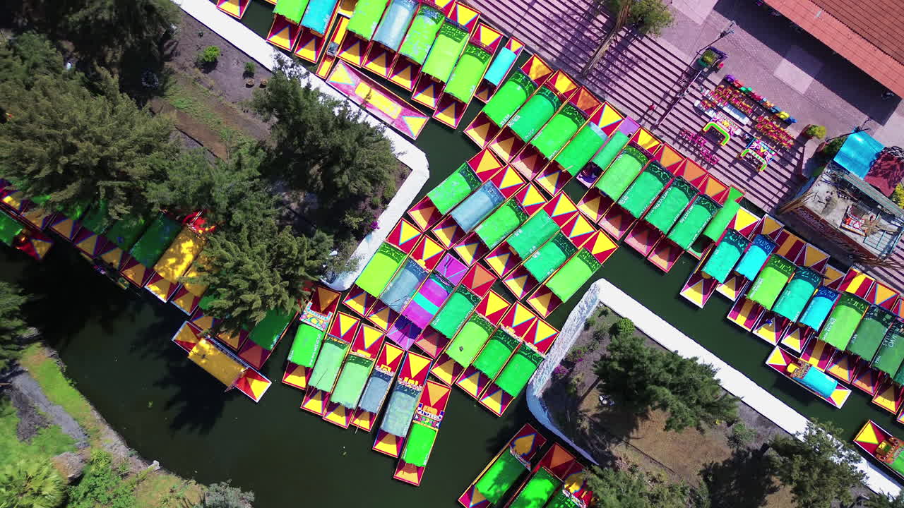 Aerial top down of vibrant Xochimilco canals and colorful gondolas in Mexico City famous waterways, orbit