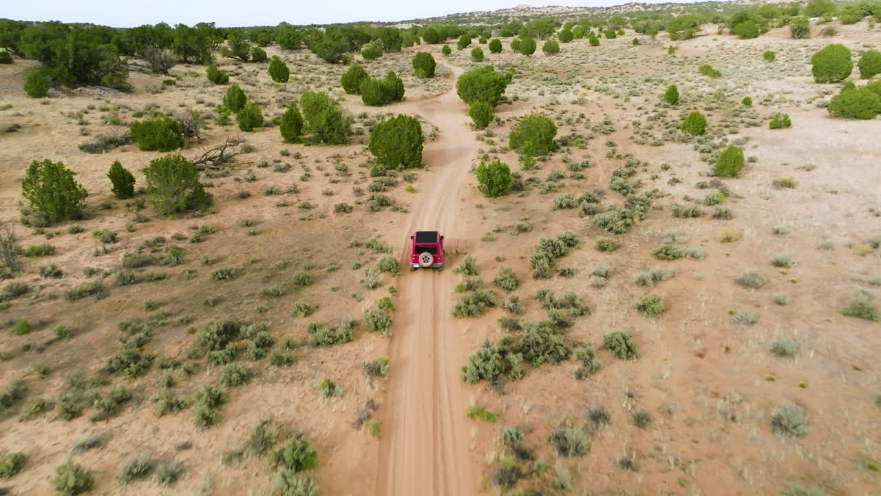 유타주 사막의 비포장 도로를 여행하는 빨간색 지프 랭글러 - 공중 드론 촬영