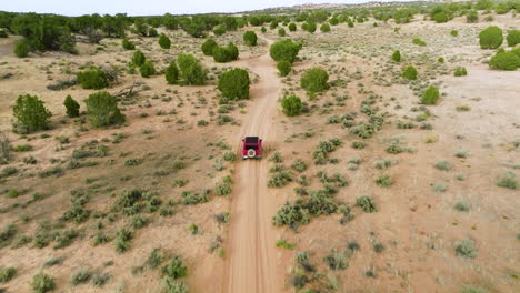 Roter-Jeep-Wrangler,-Der-Durch-Die-Unbefestigte-Straße-Der-Wüste-In-Utah-Fährt---Luftdrohnenaufnahme