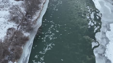 drone shot of ice floating down a river surrounded by snow in washington state