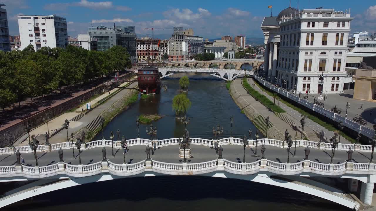 Drone retreating on Vardar River in Skopje City Centre with reveal of Art Bridge - Skopje, Macedonia