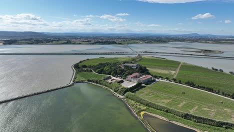 maguelone cathedral near the mediterranean coast of france with natural preserve lagoons, aerial flyover shot