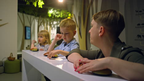 woman talking with her toddler daughter and son during a museum visit, close up