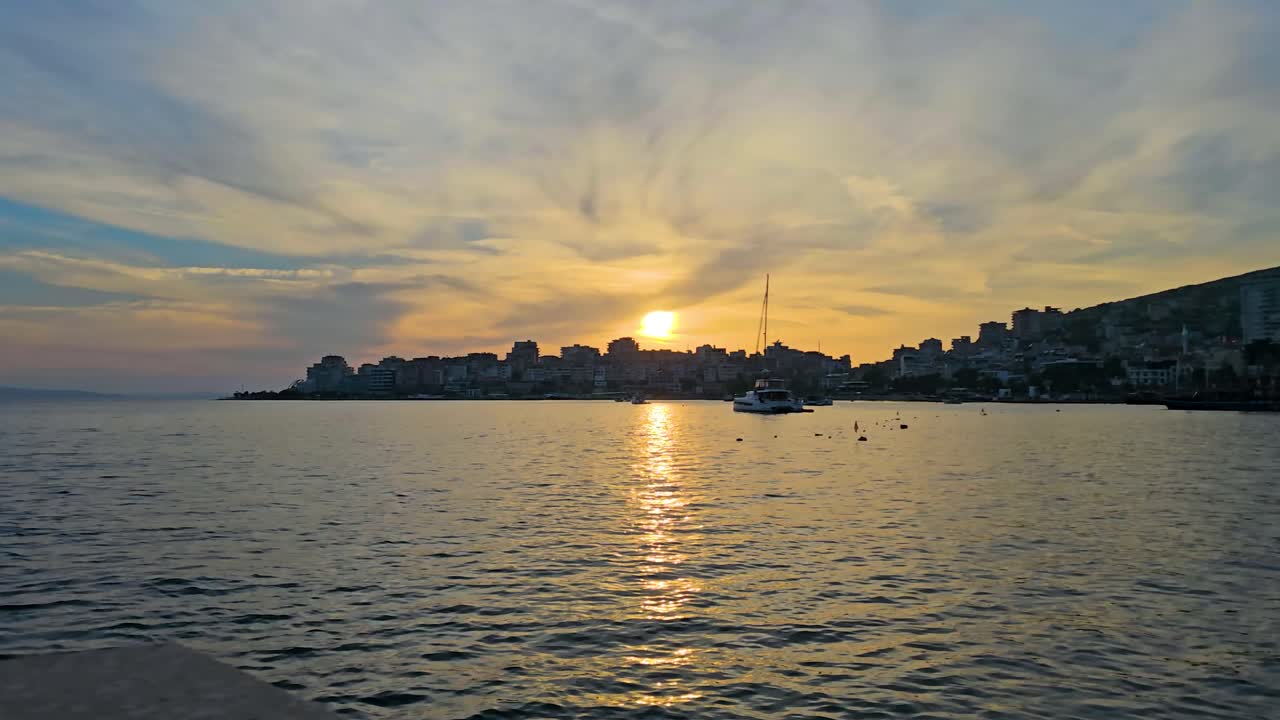 saranda ciudad costera puesta de sol mágica, puerto y bahía, mar brillante, cielo pintado con nubes vibrantes - una espectacular escena vespertina